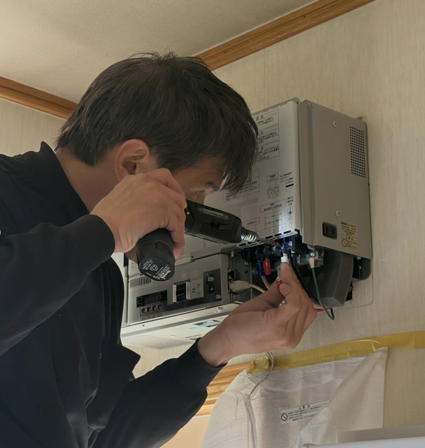 電動ドライバーでパワコン本体を壁面に固定している作業｜株式会社宮崎材木家具卸 施工事例